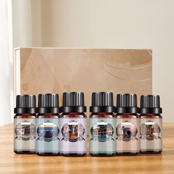 Six amber 10 ml fragrance oil bottles with colored picture labels in front of the cream and gold gift box