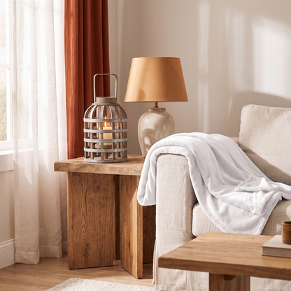 Silver wooden lantern on an oak side table next to a ceramic lamp
