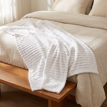 White ribbed fleece throw across the foot of a bed