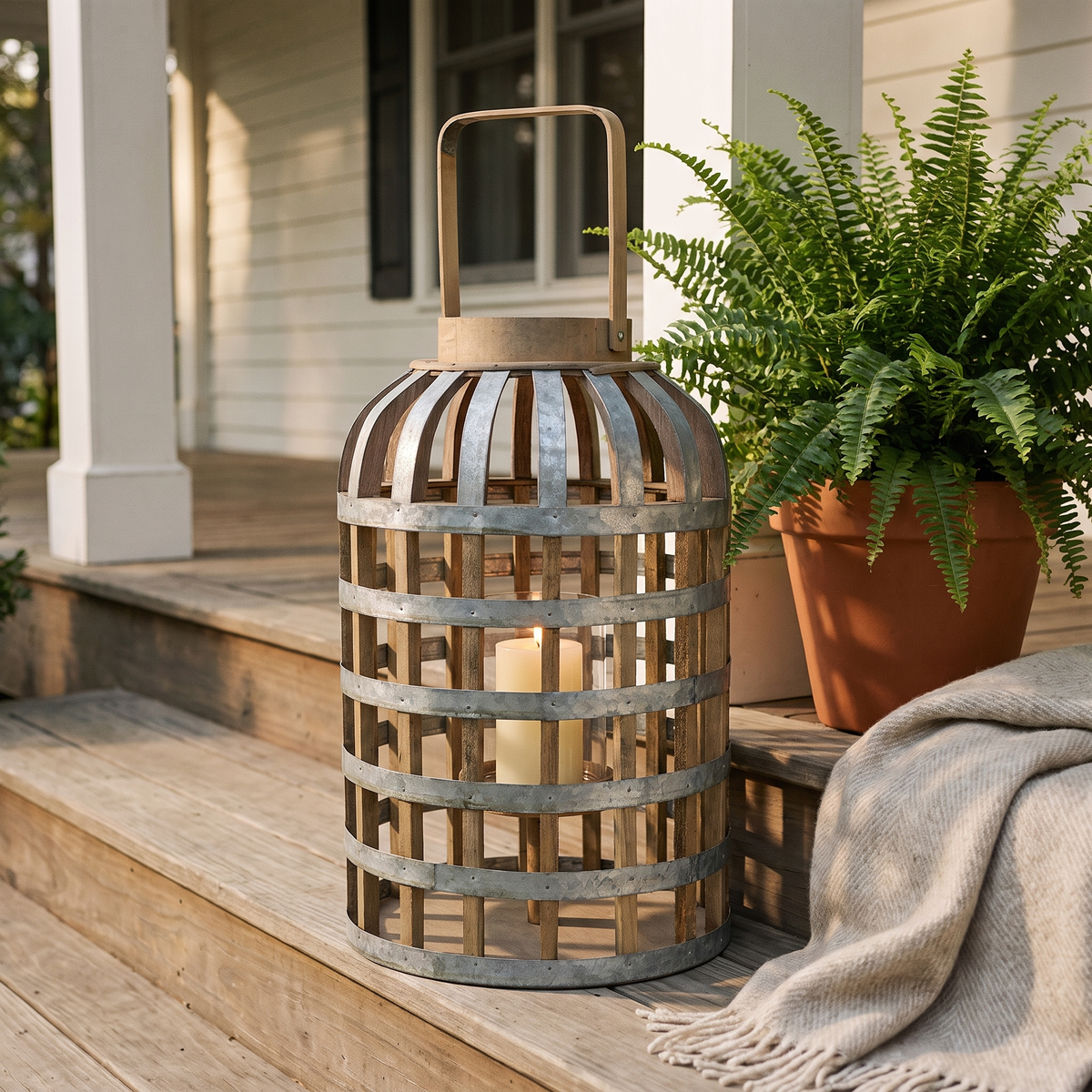 Decorative lantern with a pillar candle on wooden porch steps