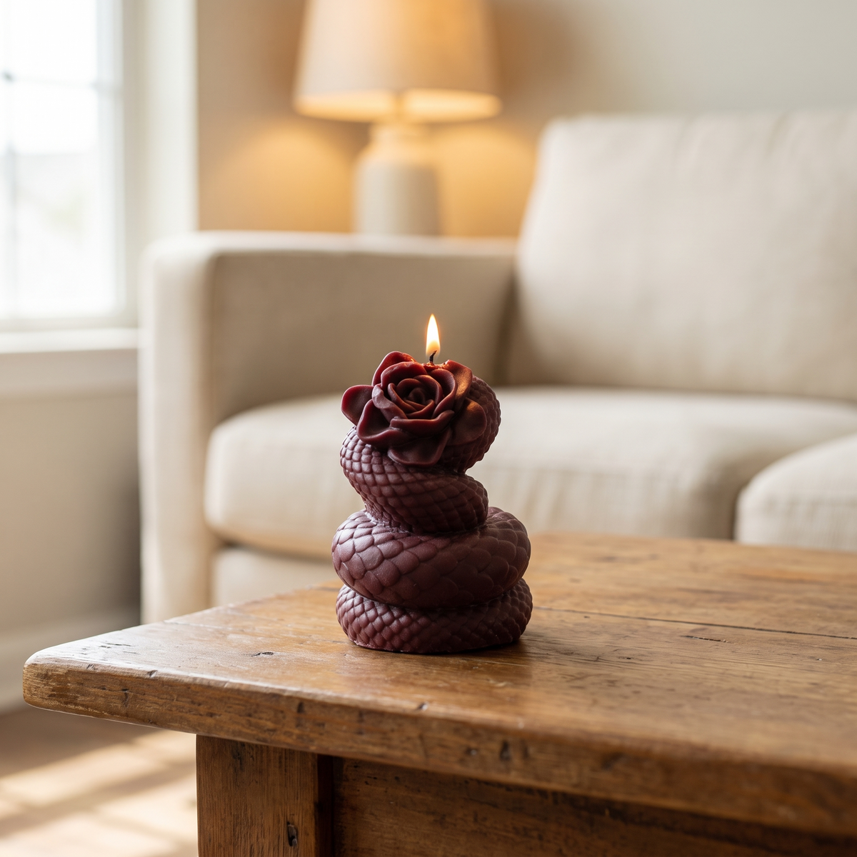 Snake Rose sculpted candle: burgundy coiled snake with a small rose on top, on a wood coffee table